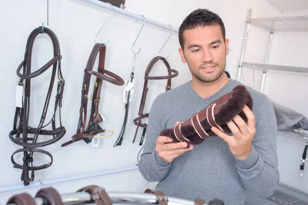 Man kijken shin pads in een Paardensport winkel — Stockfoto