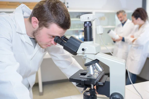 Νεαρός γιατρός επιστήμονας με μικροσκόπιο — Φωτογραφία Αρχείου