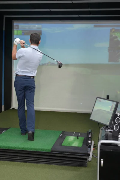 Člověk cvičit golf na indoor trenažéru — Stock fotografie