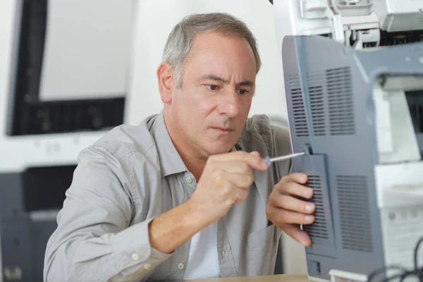 Mand håller en skruvmejsel för skrivaren repairation — Stockfoto