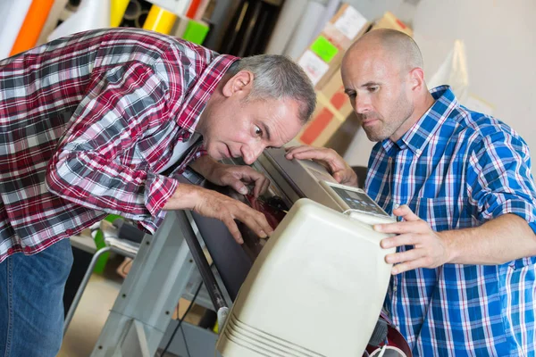 Skrivaren kontrollerar kvaliteten på sin maskin medan utskrift pågår — Stockfoto