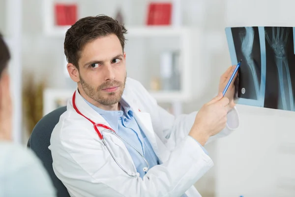 Arzt mit Patient schaut sich Röntgenbild im Büro an — Stockfoto