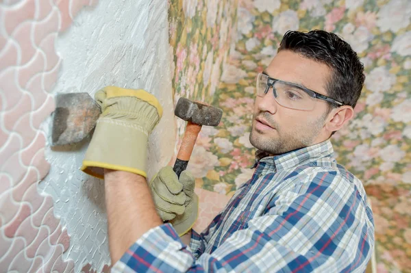 Costruttore scheggiando piastrelle da un muro — Foto Stock