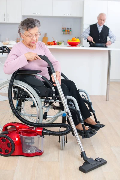 Donna anziana in sedia a rotelle pulire la sua casa — Foto Stock