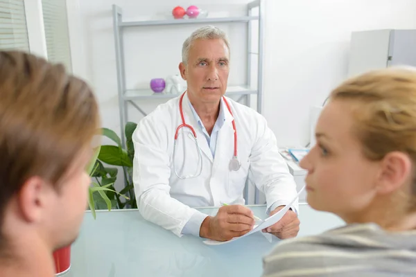 Médico en consulta con pareja joven —  Fotos de Stock