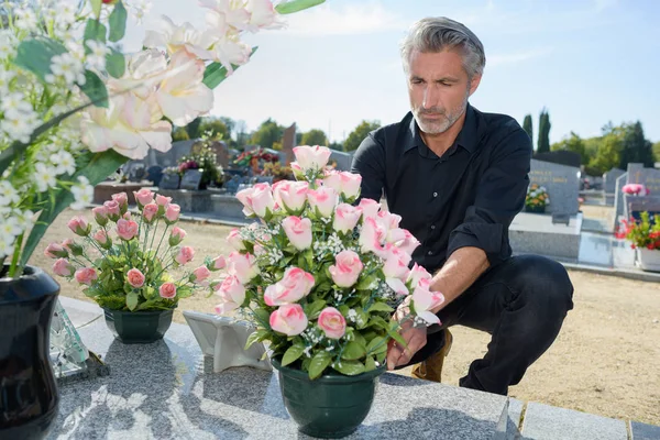 Homem organizando flores no túmulo — Fotografia de Stock