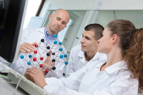 Studenten en leraar kijken model vertegenwoordigen dna-moleculen — Stockfoto