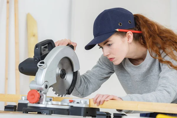 Giovane falegname femminile utilizzando una sega circolare in un laboratorio — Foto Stock