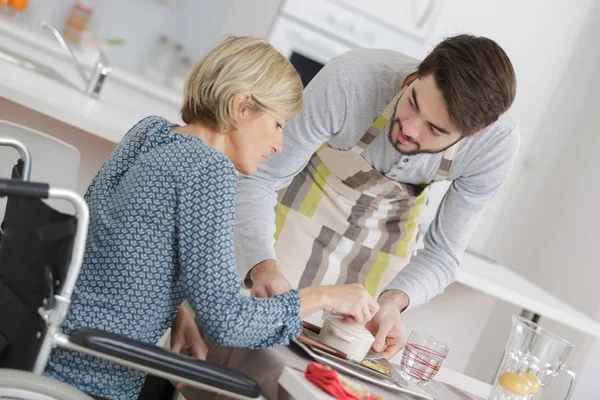 Oman in rolstoel zitten met mannelijke assistent — Stockfoto