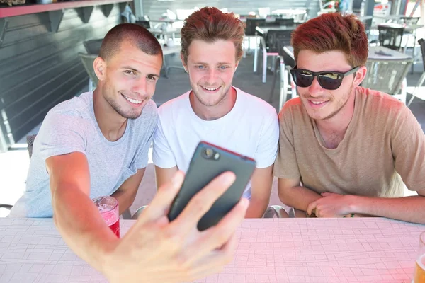 Tres jóvenes tomando selfie mientras están sentados en el pub —  Fotos de Stock