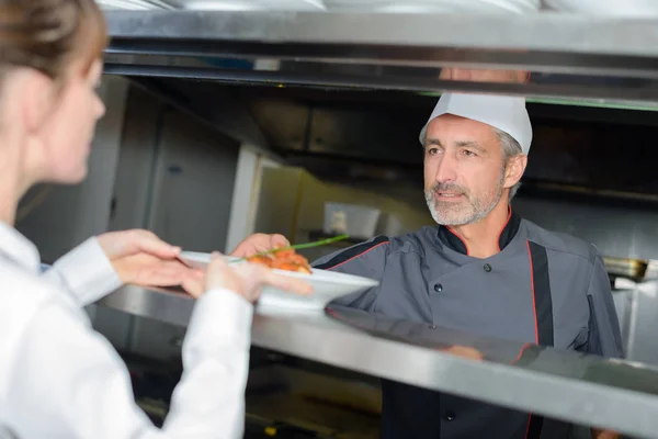 Chef colocando prato em servir escotilha — Fotografia de Stock