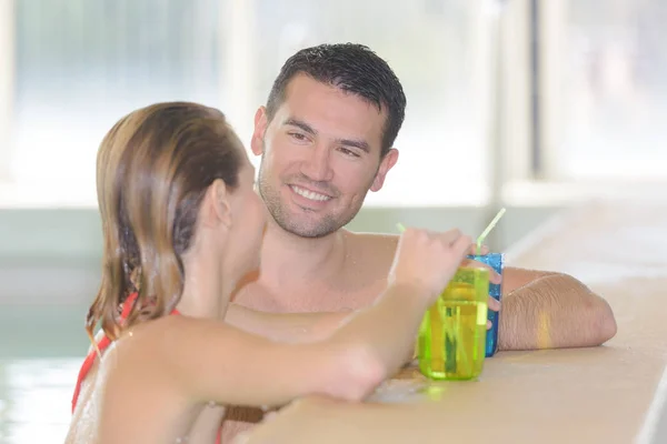 Couple drinking cocktail in swimming pool — Stock Photo, Image