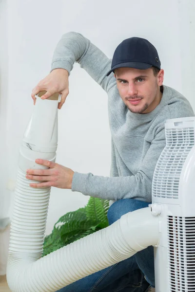 Jovem técnico instalar sistema de ar condicionado dentro de casa — Fotografia de Stock