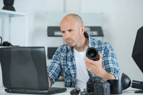 Mann hält Kamera während er am Arbeitsplatz sitzt — Stockfoto