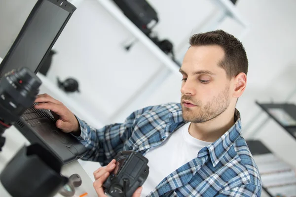 Fotografen kontrollera bilder i kameran på skrivbord i office — Stockfoto