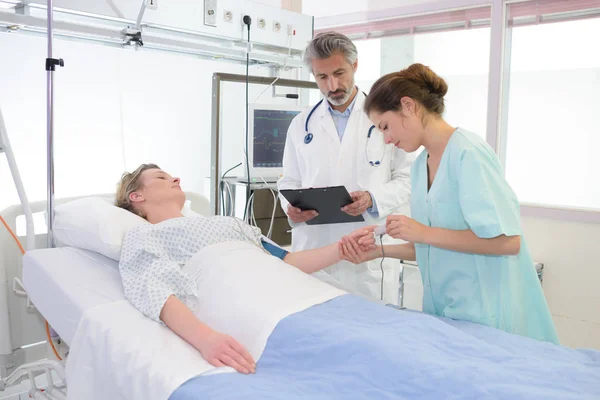 Pane doktore vyšetřují pacientky ležet na posteli v nemocnici — Stock fotografie