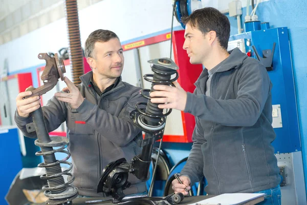 Mechaniker und männlicher Auszubildender mit Dämpfern — Stockfoto