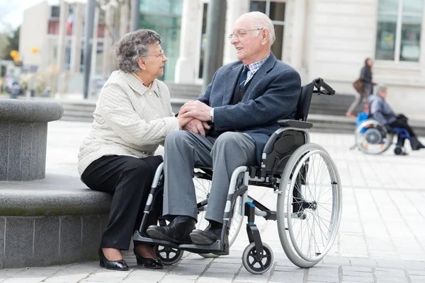 Senior im Rollstuhl mit liebender Frau neben ihm — Stockfoto