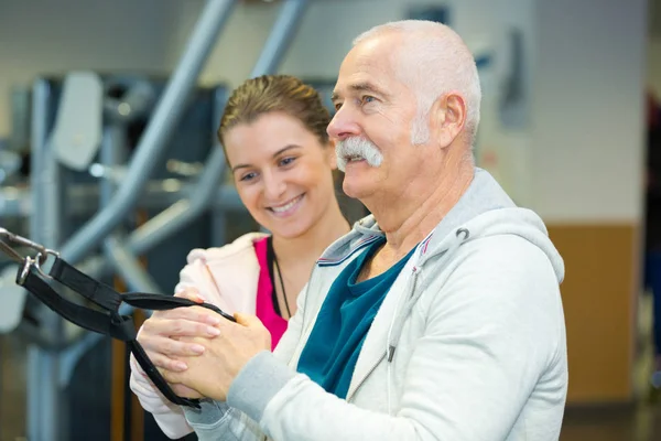 Ouderen man trekken gewichten tijdens de training sessie — Stockfoto