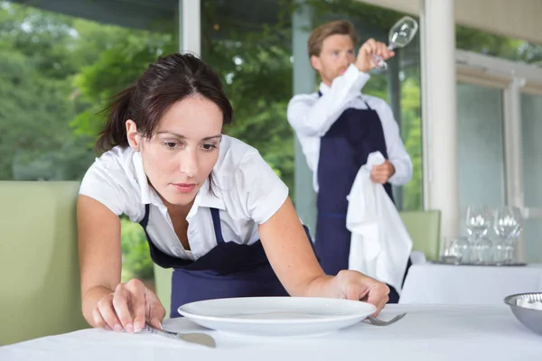 Garçonete colocando utensílios de mesa em posições exatas — Fotografia de Stock