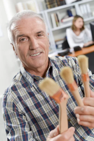 Senior painter holding paintbrushes — Stock Photo, Image