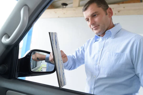 Jonge mannelijke werknemer auto voorruit met doek en Spray reiniging — Stockfoto