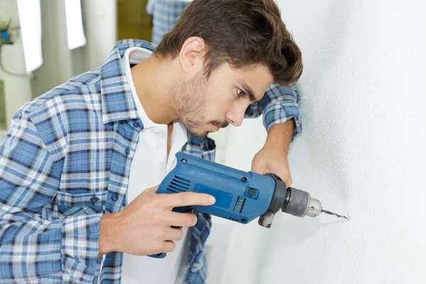 Constructor masculino perforando agujeros en la pared en el sitio de construcción —  Fotos de Stock