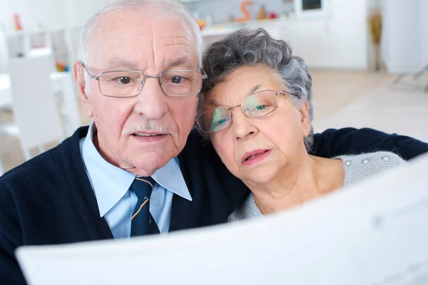 Casal sênior lendo jornal juntos em casa — Fotografia de Stock