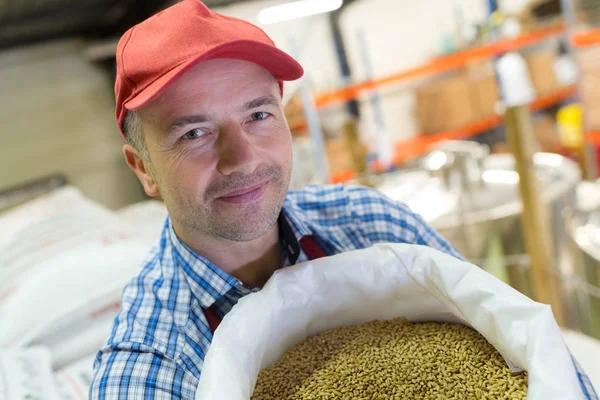 Handsome mature worker holding bag of malt — Stock Photo, Image