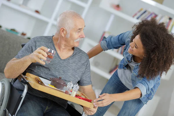 Vrouwelijke conciërge serveren van het ontbijt aan senior man thuis verpleging — Stockfoto