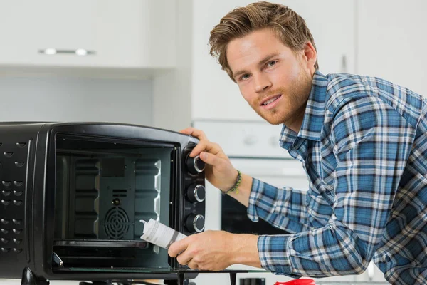 電子レンジのフィルター交換後に掃除する男 — ストック写真