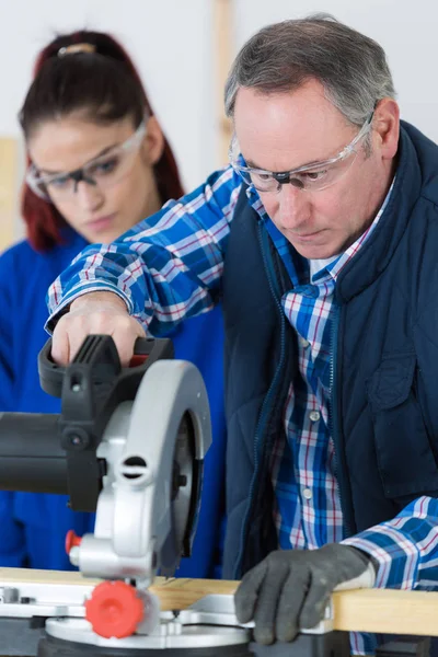 Student and teacher in carpentry class using circular saw — Stock Photo, Image