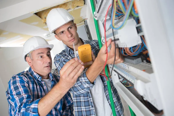 Joven aprendiz con electricista profesional — Foto de Stock