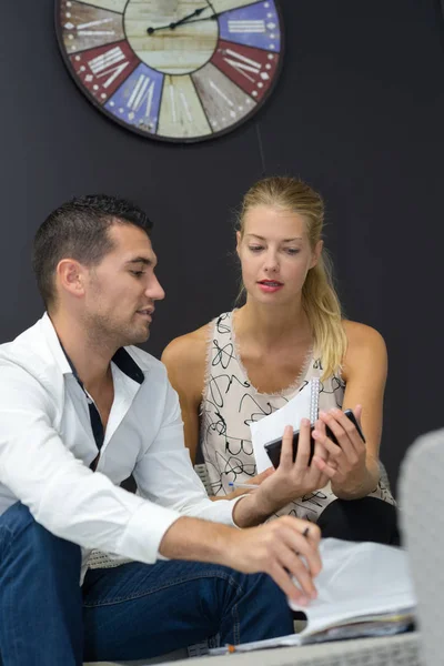 Couple is using a smartphone waiting at an office — Stock Photo, Image