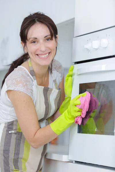 Mujer joven limpiando el horno con una esponja —  Fotos de Stock