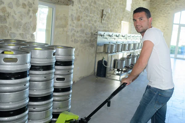 Porträt eines Herstellers, der Fässer in Brauerei trägt — Stockfoto