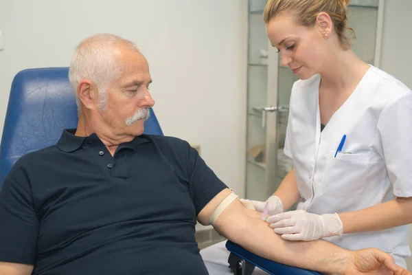 Médico fazendo exame de sangue para homem sênior — Fotografia de Stock