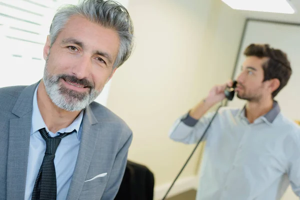 実業家、バック グラウンドで電話で同僚の肖像画 — ストック写真