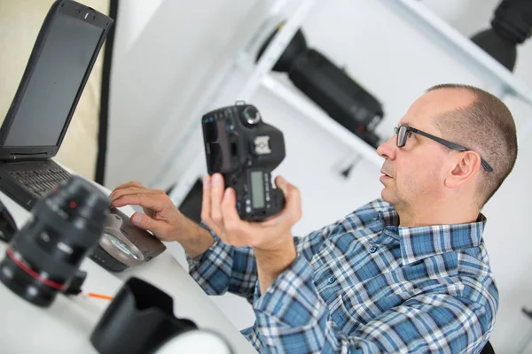 Техник, осматривающий и ремонтирующий камеру dslr — стоковое фото