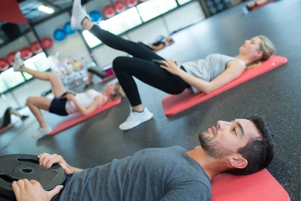 Άνθρωποι κάνουν σωματικές ασκήσεις στο πάτωμα στο γυμναστήριο — Φωτογραφία Αρχείου