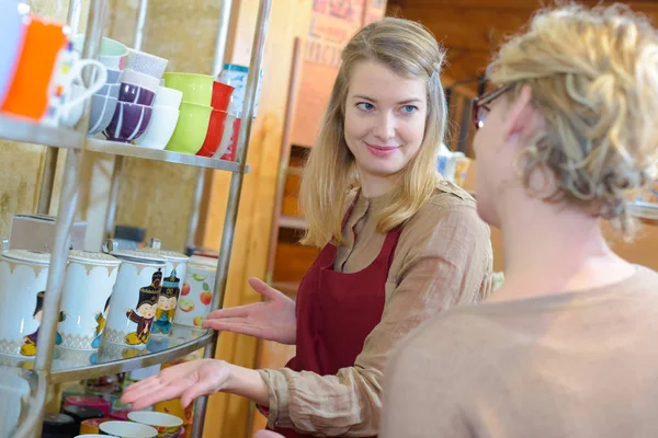 Vrouw wordt bijgestaan om te kiezen van cup in een winkel — Stockfoto