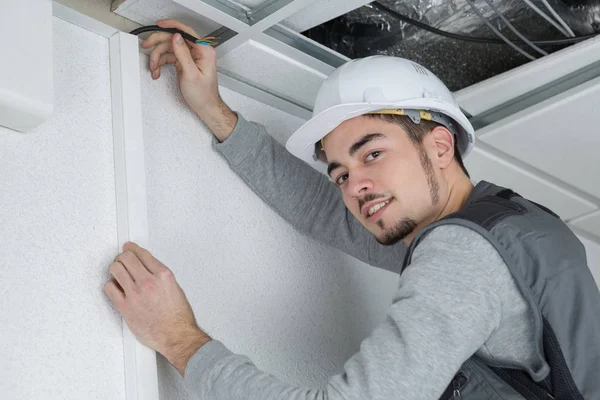 Portret van man die draad boven aan muur houden — Stockfoto