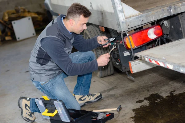 Механик с помощью отвертки на грузовике в ремонтном гараже — стоковое фото