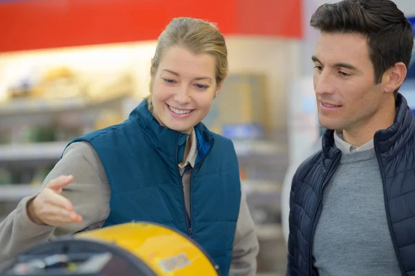 Negoziante femminile utile che mostra il prodotto al cliente — Foto Stock