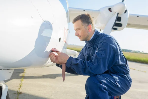 Mecánico agachado trabajando en el lado de la aeronave — Foto de Stock