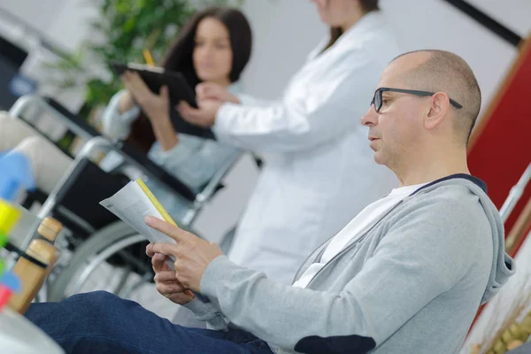 Uomo che legge documenti in sala d'attesa medica — Foto Stock