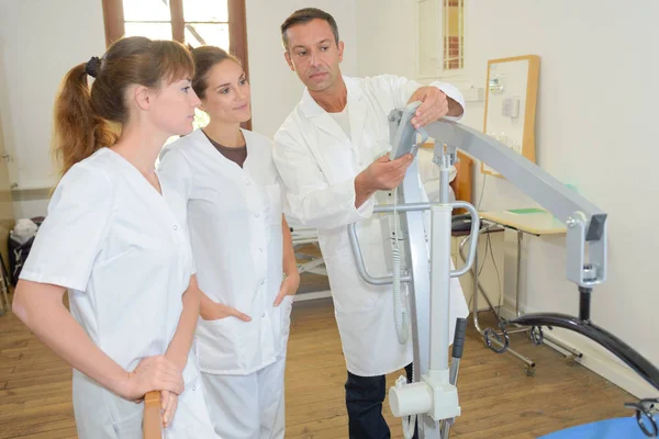 Two homecare nurses learning how to use a hoist — Stock Photo, Image