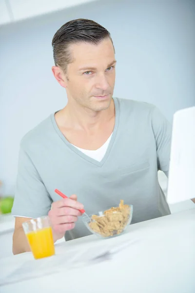 Retrato de homem comendo cereais e surfando em um tablet — Fotografia de Stock