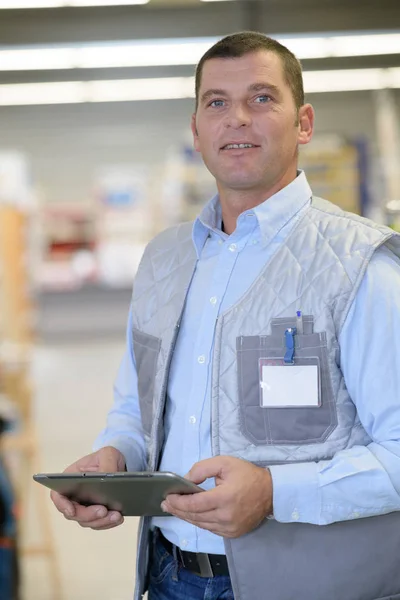 Trabalhador sorrindo com tablet no armazém — Fotografia de Stock