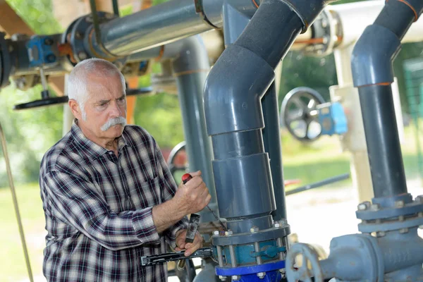 Anciano trabajando en una sección de tubería de pvc de agua — Foto de Stock